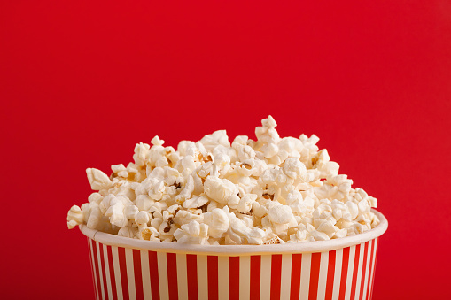 Striped box with heap of popcorn on blue background