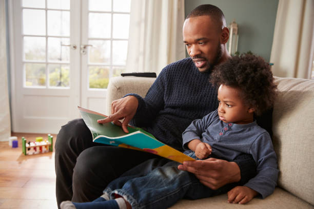 istock Father And Young Son Reading Book Together At Home 961758556