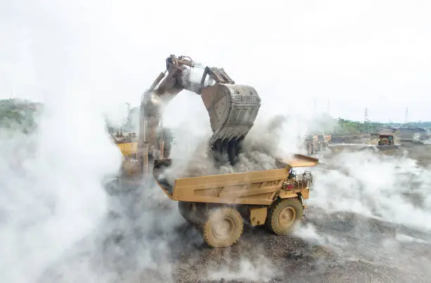 Backhoe load Hot and smokey foggy material into mining dump truck in Nickel Mining in South Sulawesi, Indonesia.
