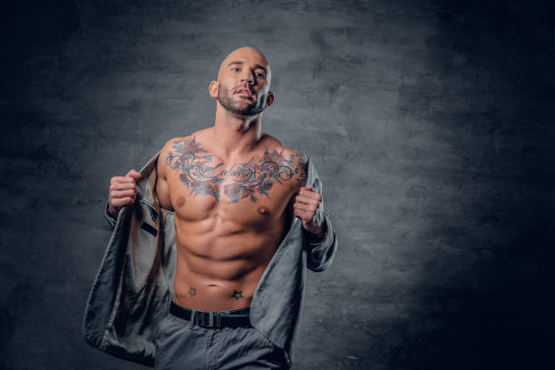 istock Shaved head tattooed male dressed in a grey jacket on a naked torso. 961764512