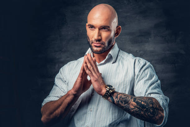 istock Praying shaved head man with tattoos on his arm. 961764696