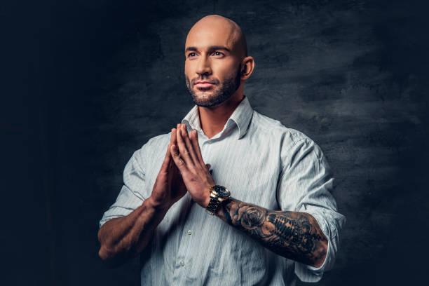 istock Praying shaved head man with tattoos on his arm. 961765436