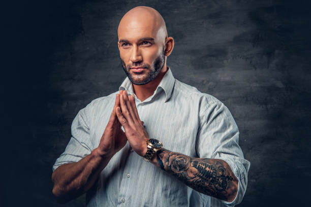 istock Praying shaved head man with tattoos on his arm. 961768280