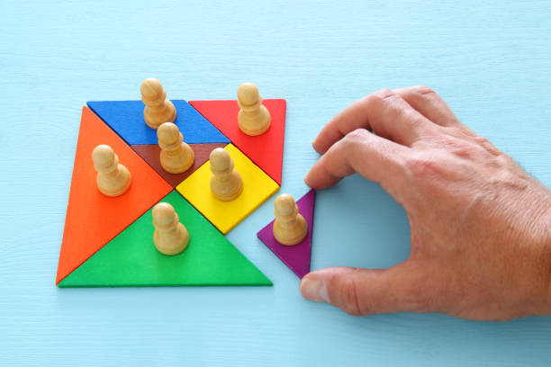 istock image of tangram puzzle blocks with chess figures over wooden table ,human resources and management concept. 961768826