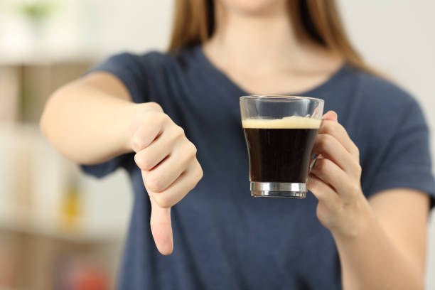 Woman hands holding a coffee cup with thumbs down stock photo