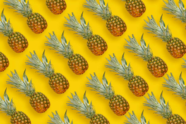 istock pineapple pattern. many pineapples on bright yellow paper background, trendy flat lay. summer concept 961774056