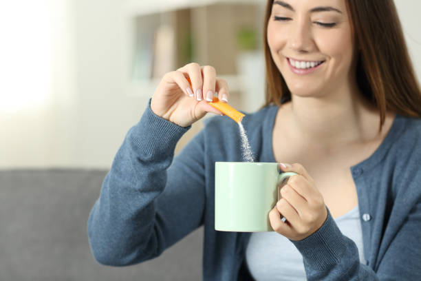 frau zucker in einen becher zu werfen - sugar sachet stock-fotos und bilder