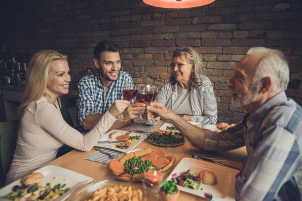 Cheers to lovely meal with family! Happy adult children and their parents toasting with wine during lunch time in dining room father in law stock pictures, royalty-free photos & images