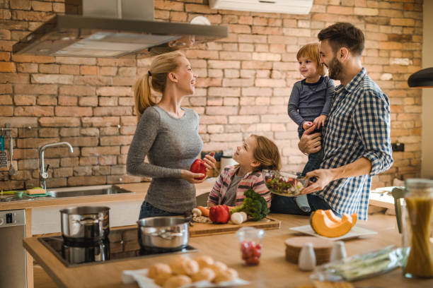 istock Happy parents talking to their kids while preparing meal in the kitchen. 961782398