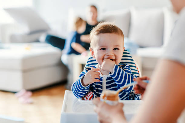 Mothe feed a baby by blue spoon in family room, Home and family concept