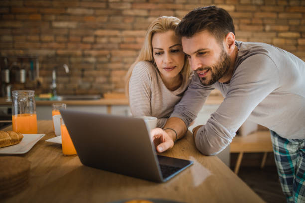 istock Young smiling couple using laptop in the kitchen. 961783384