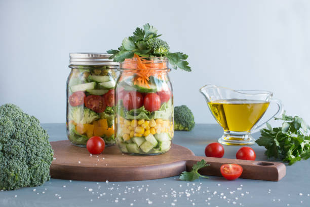 istock Vegetable healthy homemade salad in mason jar with tomato, lettuce, broccoli on blue. Copy space. Lunch for work. 961783708