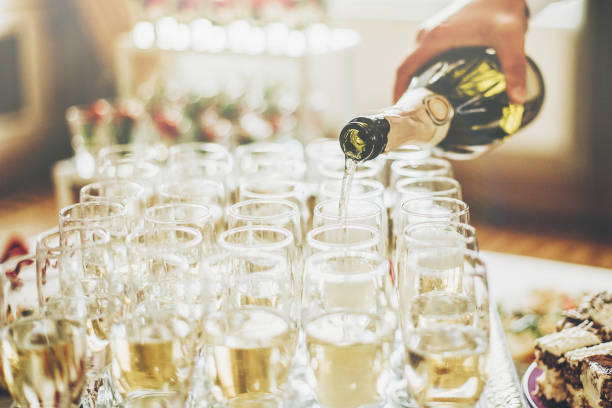 waiter pouring champagne in stylish glasses at luxury wedding reception. rich celebration. expensive catering and service at feast. new year and christmas celebrations and drinks - wedding champagne table wedding reception imagens e fotografias de stock