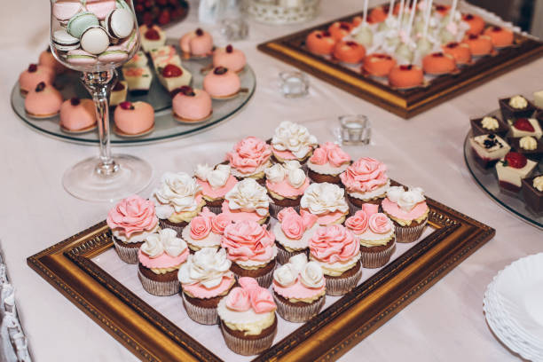 istock delicious sweets cupcakes with roses,pops and candy on table at wedding reception. candy bar. tasty pink sweets for celebrations events and showers. luxury stylish catering 961798260