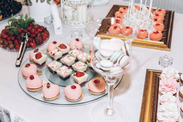 istock delicious sweets cupcakes with roses,pops and candy on table at wedding reception. candy bar. tasty pink sweets for celebrations events and showers. luxury stylish catering 961798306