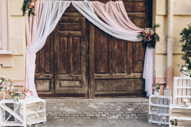 rustic wedding photo zone. wooden barn doors with fabric and white boxes with flowers and candles at stylish wedding photo booth. shabby chic. luxury arrangements