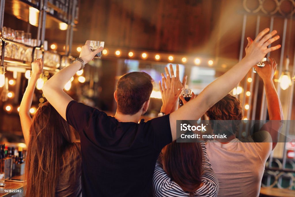 Group of friends watching soccer in pub Group of friends watching soccer game in pub Bar - Drink Establishment Stock Photo