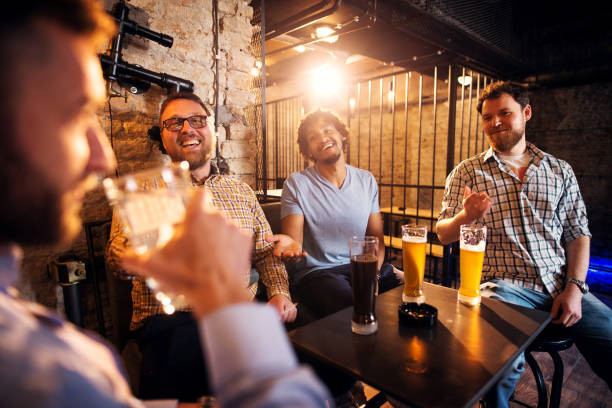istock Four happy casual multicultural friends having fun and drinking beer while sitting in the pub. 961827398