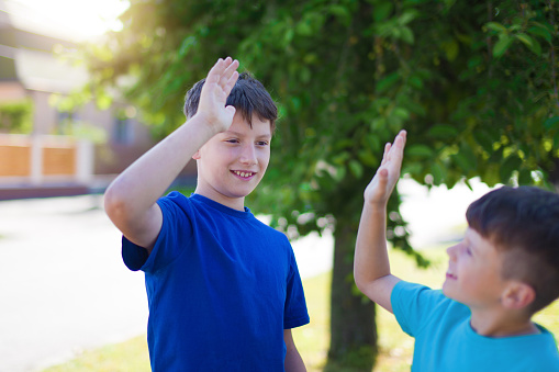 Happy young little brothers high five outdoor