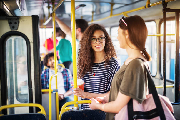 istock Two beautiful young women are drinking coffee and having a chat while standing in the bus and holding onto the bars. 961833780