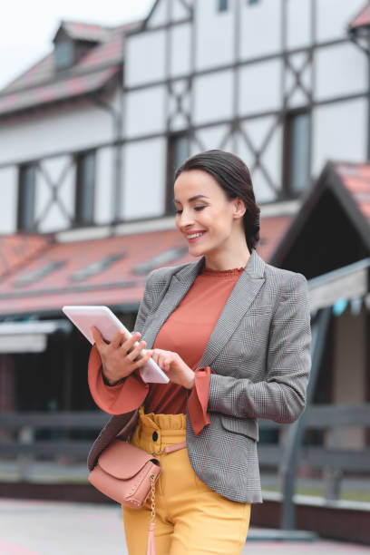 istock beautiful stylish woman using tablet in city 961834460