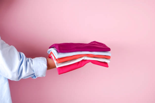 istock Female holding a pile of folded clothes, unisex for both man & woman, different color & material. Trip preparation concept. 961836708