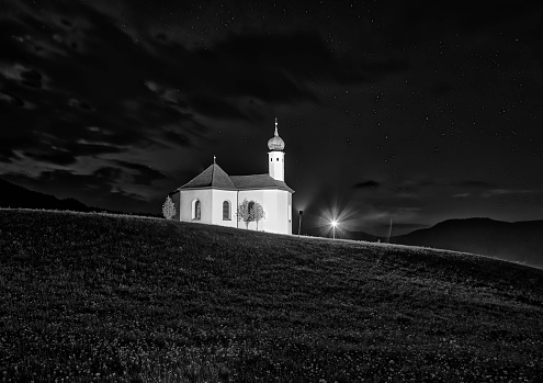 night shot of the Alp mountains with a small Sankt Anna church on the hill; Achenkirch, Austria
