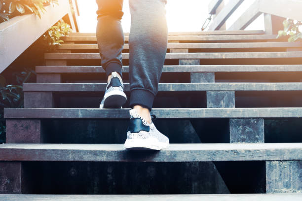 a man step up to success, sport man is climbing on wooden step - black ladder white staircase imagens e fotografias de stock