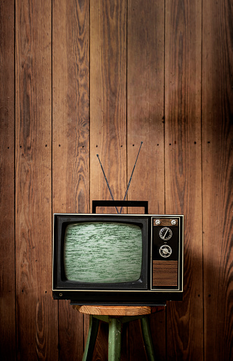 Old TV in front of wooden wall