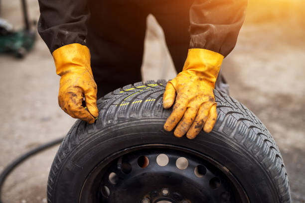 istock Mechanic with orange gloves is using chalk to mark tires while leaning on one in his workshop. 961841056