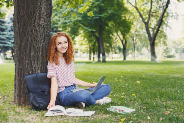 istock Attractive student with laptop and notebook outdoors 961842408