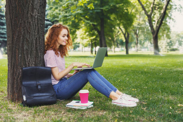 istock Happy young woman using laptop in park 961842506