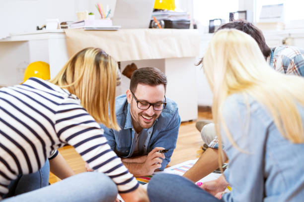 istock Young cheerful group of designer people sitting and laying on the floor while deciding which colour to pick. 961845236