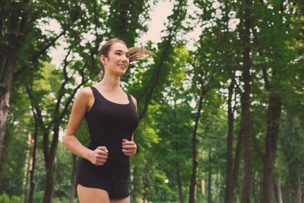 istock Young woman jogging in green park, copy space 961847308