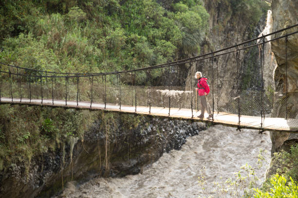 istock Woman walks over bridge spanning river gorge 961850006
