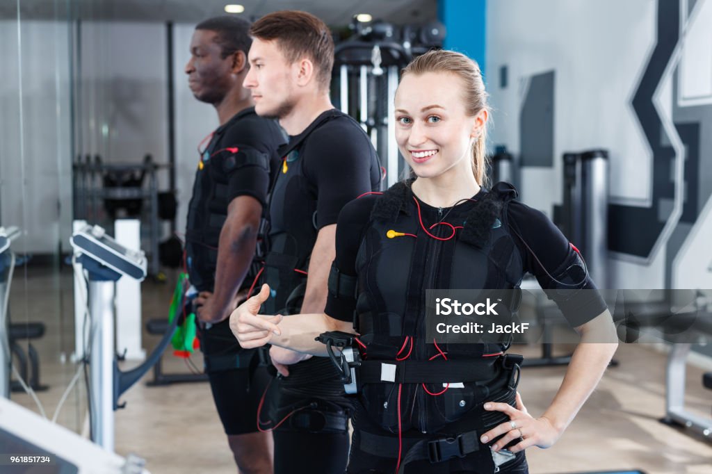 Athletic  girl during electric muscle stimulation workout in fitness gym Athletic  smiling cheerful  girl during electric muscle stimulation workout in fitness gym Electro Music Stock Photo