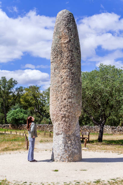 woman looking at the standing stone / menhir of meada, the largest of the iberian peninsula. - castelo de vide imagens e fotografias de stock