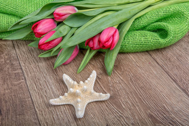 Concept of starfish and tulips on a wooden table
