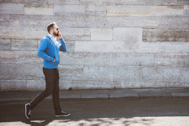 istock young man walking and talking on the phone 961857004
