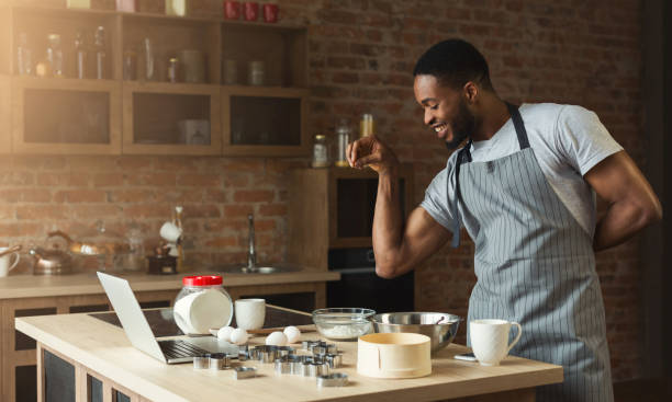hombre afroamericano hornear galletas en casa cocina - home baking fotografías e imágenes de stock