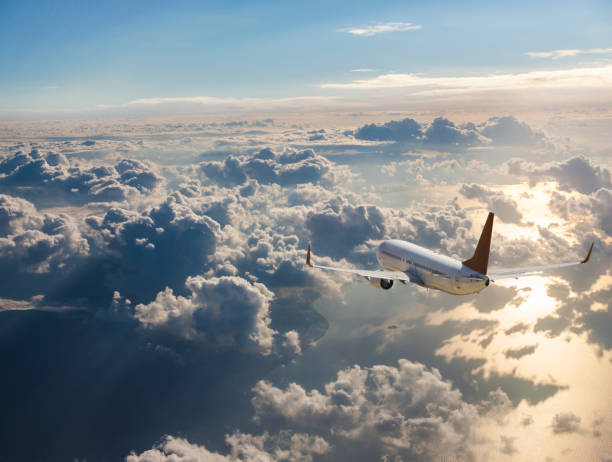 Passenger airplane flying above clouds at sunrise