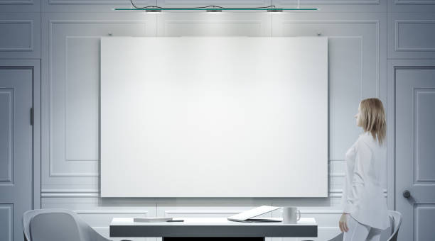 istock White office interior with blank poster, person stand mockup 961875214