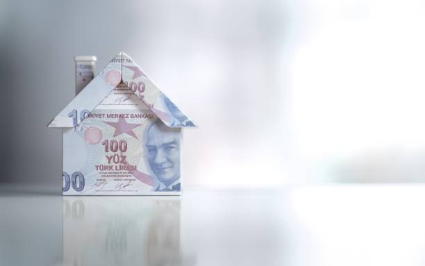 istock Tiny House Model Textured With One Hundred Turkish Lira Banknotes On Reflective Surface 961877612