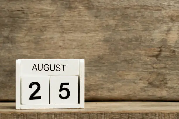White block calendar present date 25 and month August on wood background