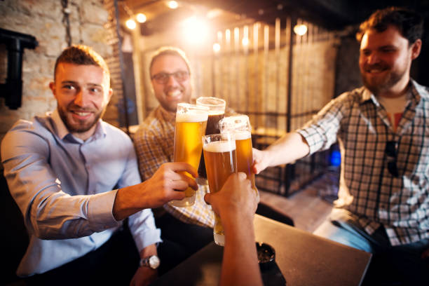 istock A group of young cheerful men clinking glasses with a beer in the sunny pub after work. 961881736