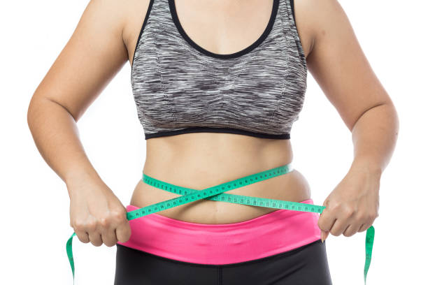 Overweight woman check out his body fat with green measuring Overweight woman check out his body fat with green measuring tape for obesity on gray background, Healthy concept exercising tape measure women healthy lifestyle stock pictures, royalty-free photos & images