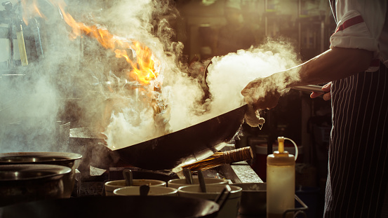 Chef is stirring vegetables in wok, vintage filter