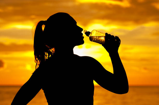 istock Silhouette of young athletic woman drinking water 961889704
