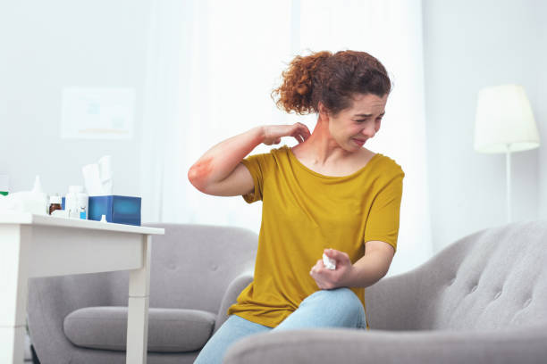 Young woman suffering from a neck sprain Sore neck. Young woman sitting on a grey couch suffering from a painful neck sprain giving her trouble in motion ehlers danlos syndrome symptoms stock pictures, royalty-free photos & images