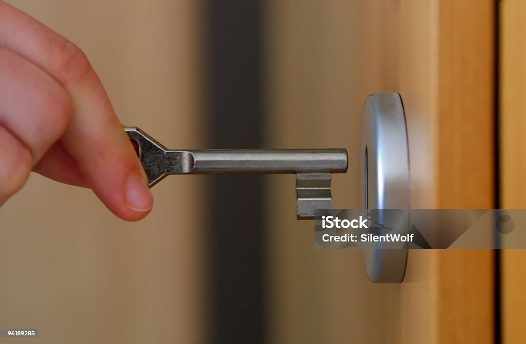 Close-up of fingers inserting a key into a door lock Hand holding key (with key hole) Locking Stock Photo